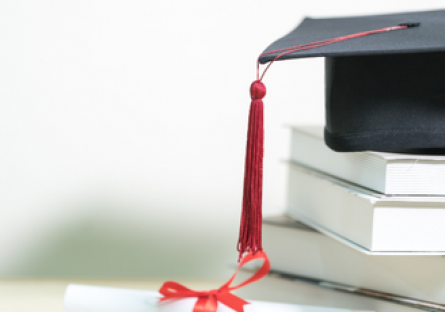 A stack of books with a graduation cap on top
