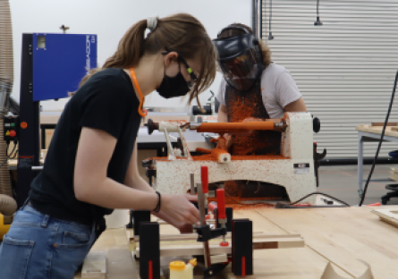 An image of a female Phoenix Forge member using woodworking tools. 