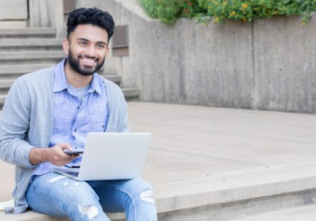 An image of a man sitting on steps using a laptop