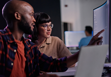 A man and woman sitting side by side looking at a computer monitor